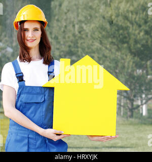 Happy smiling female worker in hardhat holding house model Stock Photo