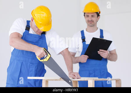 Two workmen in protective workwear with saw and folder Stock Photo