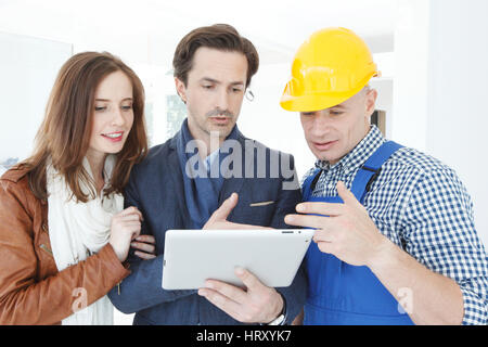 Worker and couple using tablet pc at construction site Stock Photo