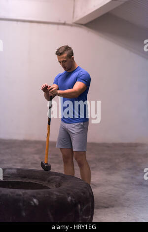 Sledgehammer Tire Hits young muscular man workout at gym with hammer and tractor tire Stock Photo