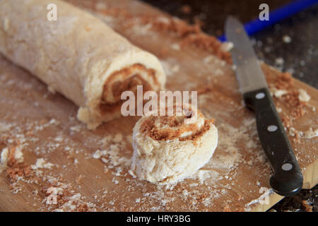 Cinnamon roll cut on wooden cutting board Stock Photo