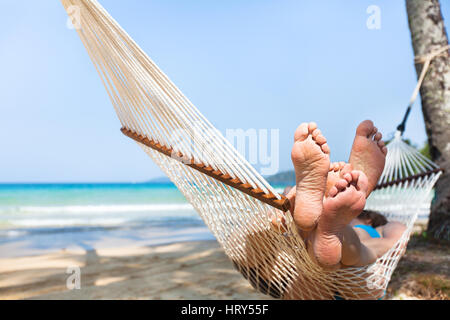 happy couple family in hammock on tropical paradise beach, island holidays, closeup of feet Stock Photo