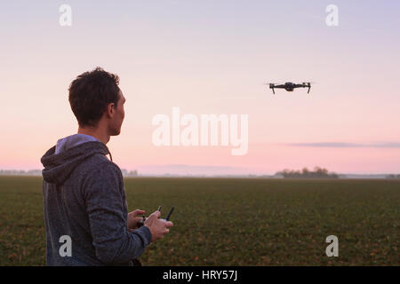 man piloting drone at sunset outdoors Stock Photo