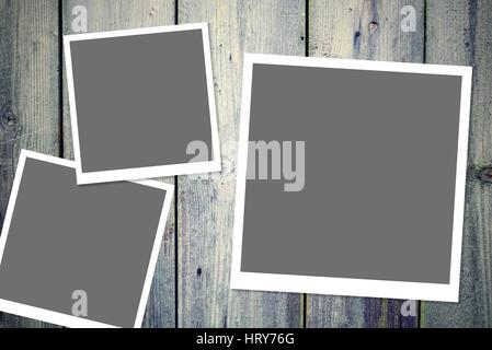 Three instant vintage white photo frames with blank gray space placed on the wooden desk. Stock Photo