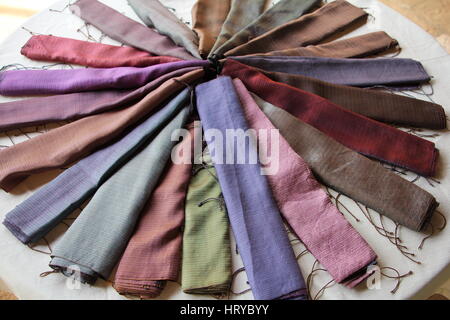 Silk scarves in a range of colours arranged in a circle on grey background Stock Photo