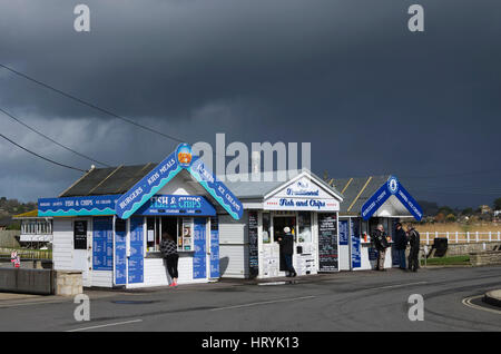 West Bay, Dorset, UK.  5th March 2017.  UK Weather.   Dark shower clouds above the Fish & Chip kiosks at West Bay in Dorset on a day of sunshine, showers and gusty winds.  West Bay is the location for the hit ITV detective drama Broadchurch. Photo Credit: Graham Hunt/Alamy Live News Stock Photo
