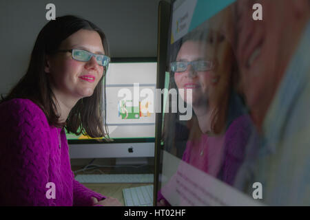 young woman looking at computer screen with reflection Stock Photo