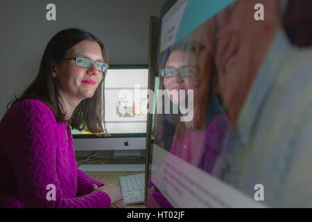 young woman looking at computer screen with reflection Stock Photo