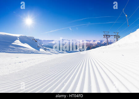 Fresh tracks of snowcat at the ski resort slopes in the early sunny morning Stock Photo