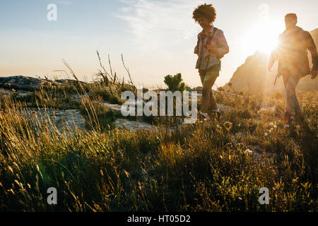 Friends on walk through countryside together. Young man and woman hiking on a summer day. Stock Photo