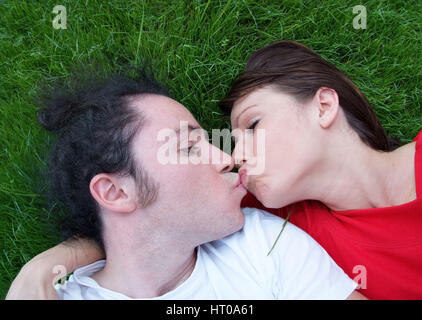 Paar liegt in der Wiese und kuesst sich - kissing couple in meadow Stock Photo