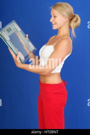 Zufriedene Frau mit K?rperwaage in der Hand, Symbolbild erfolgreiche Di?t - woman with scale Stock Photo