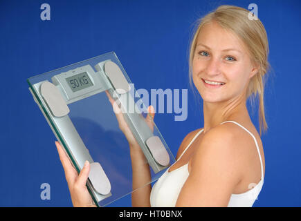 Zufriedene Frau mit K?rperwaage in der Hand, Symbolbild erfolgreiche Di?t - woman with scale Stock Photo