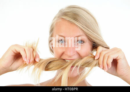 Junge, blonde Frau bei?t in ihre langen Haare - young, blond woman biting in her hair Stock Photo