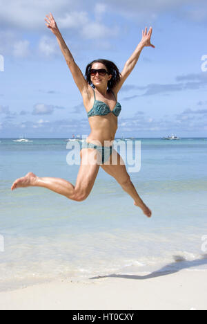 Junge, vitale Frau im Bikini springt am Strand - young woman jumping on the beach Stock Photo
