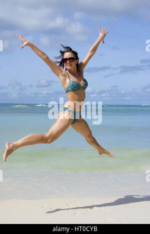Junge, vitale Frau im Bikini springt am Strand - young woman jumping on the beach Stock Photo