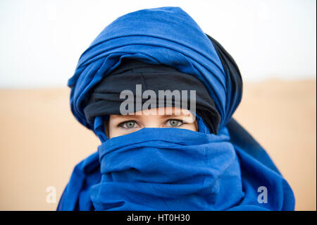 A woman with Blue Eyes wearing a blue headscalf in the Sahara Desert, Morocco Stock Photo