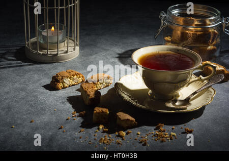 Cup of tea , tasty and healthy almond cookies, rich in vitamins, minerals in a glass jar  on a dark background. Low key. Stock Photo