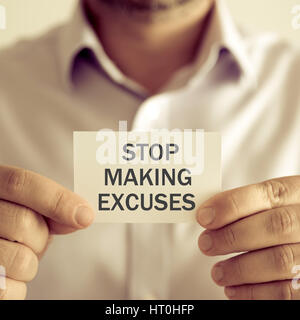 Closeup on businessman holding a card with text STOP MAKING EXCUSES, business concept image with soft focus background and vintage tone Stock Photo