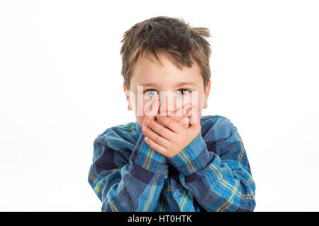 Little boy covering mouth with his hands looking straight ahead. Scared, stubborn or afraid of saying too much. Isolated on a white background. Stock Photo