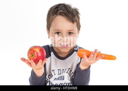 Smiley little boy holding apple and carrot. Isolated on a white background. Stock Photo