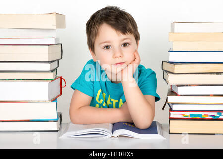 Smiling boy sitting between stack of books . Isolated on a white background. Stock Photo