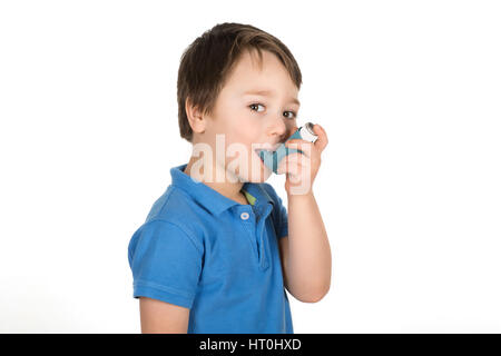 Asthmatic boy using a metered-dose blue Inhaler "Puffer". Isolated on a white background. Stock Photo
