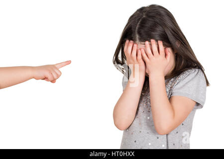 Crying school girl covering hear eyes being bullied. Finger pointing someone. Isolated on a white background. Stock Photo