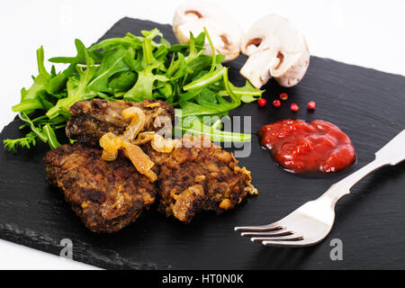 Fried liver, fresh arugula on black stone plate Stock Photo