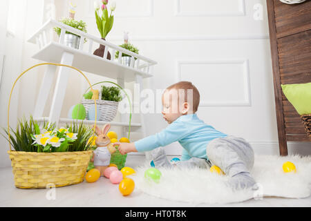 Easter egg hunt. Adorable child playing with colorful Easter eggs at home Stock Photo