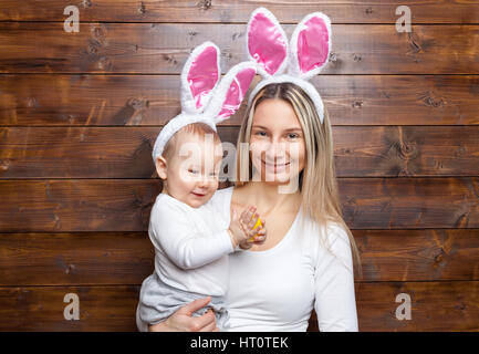Easter concept. Happy mother and her cute child wearing bunny ears getting ready for Easter Stock Photo