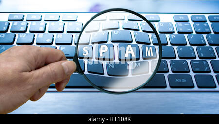 Mans hand with magnifier.Keyboard of computer or laptop with sign spam Stock Photo