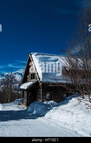 Mountain cottage in forest during snow, beautiful idyllic winter season scenery Stock Photo