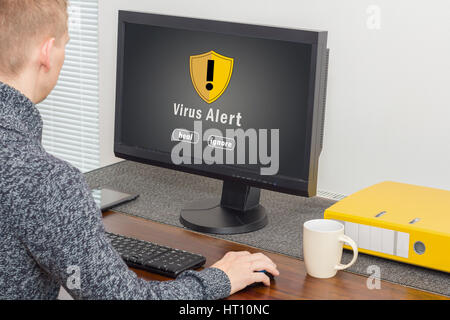 man using computer with computer virus alert Stock Photo