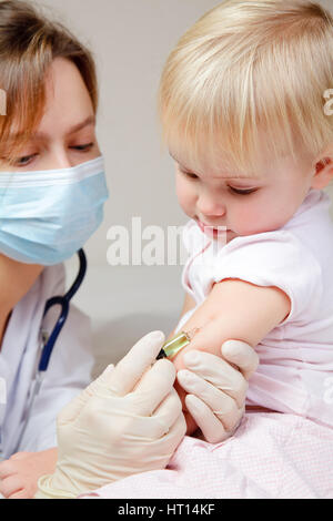 Doctor giving a child an intramuscular injection in arm Stock Photo