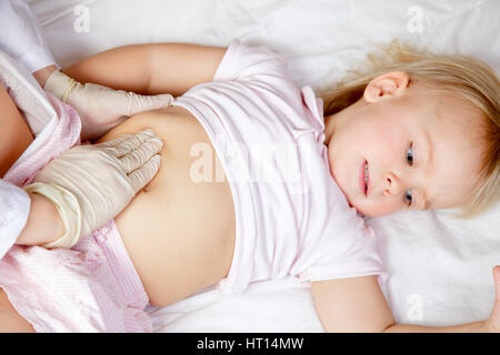 Pediatrician examining  little girl's abdomen using manual palpation Stock Photo