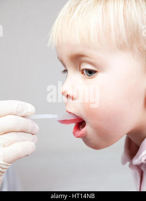 Close-up shot of pediatrician giving a dose spoon of cough syrup to little patient Stock Photo