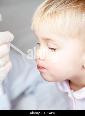 Close-up shot of pediatrician giving a dose spoon of cough syrup to little patient Stock Photo