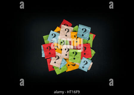 Too Many Questions. Pile of colorful paper notes with question marks on blackboard. Closeup. Stock Photo