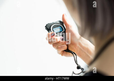 back view of sporty woman holding stopwatch in hand Stock Photo