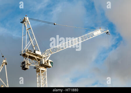 Construction crane boom against a blue sky with grey clouds Stock Photo