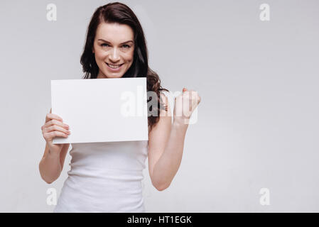 All in our hands. Confident independent motivating lady clenching her fist and striking a powerful pose while holding a white sign Stock Photo