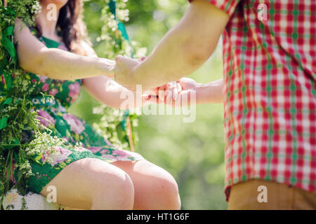 couple sitting on swing in park. Green garden. Stock Photo