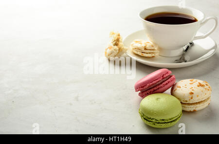 Cup of black tea with varicolored macaroons  on a white background in light key. Copy space. Stock Photo