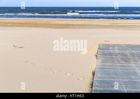 Pier on the beach promenade in Swinoujscie, Poland. A seagull is resting in the sand. Stock Photo