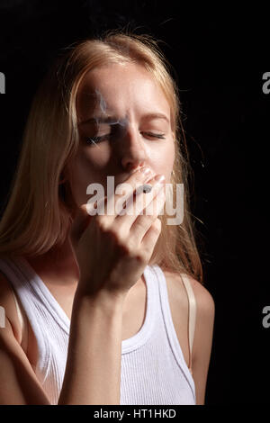sad blond girl smoking joint with marijuana Stock Photo