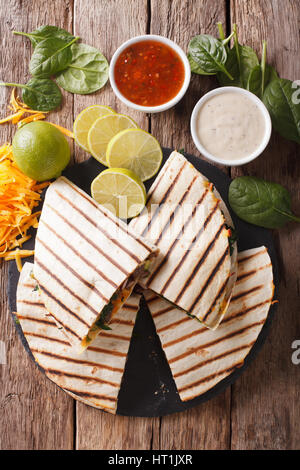 quesadilla with meat, spinach and cheddar cheese close-up on the table. vertical view from above Stock Photo
