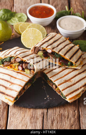 Mexican quesadilla with ground beef, spinach and cheddar cheese close-up on the table. vertical Stock Photo