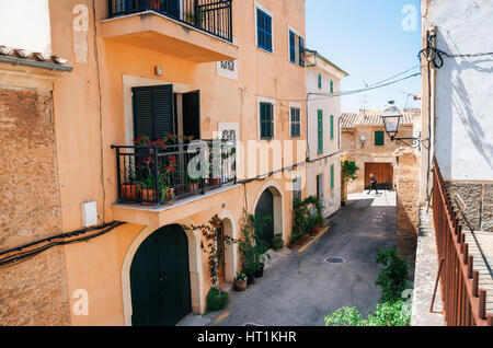 Alcudia, Mallorca, Spain - May 23, 2015: Adult walks through the narrow streets of historical town part of Alcudia with its traditional house and arch Stock Photo