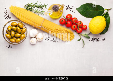 Frame with spaghetti and various ingredients for cooking pasta on a white background, top view. Flat lay Stock Photo